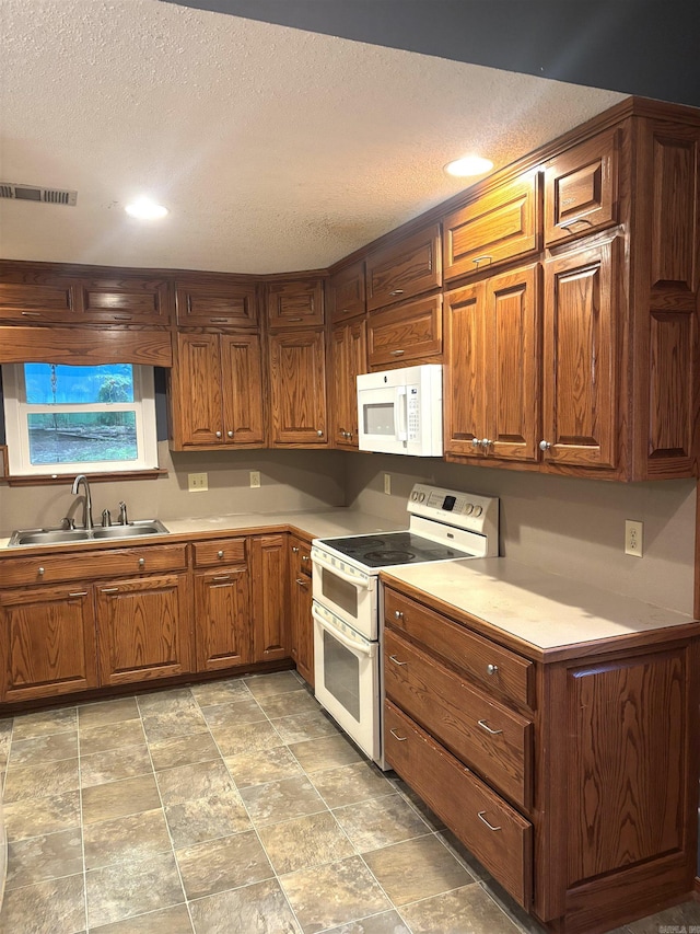 13 Page Cv, Maumelle, AR 72113 - kitchen featuring white appliances, a sink, a textured ceiling, brown cabinets, and light countertops