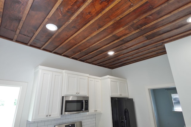 1365 Mitchell St, Conway, AR 72034 - kitchen view of stainless steel microwave, black fridge with ice dispenser, white cabinets, recessed lighting, and wooden ceiling