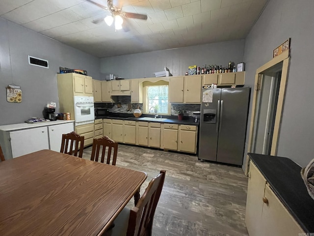 210 Gann St, Mena, AR 71953 - kitchen featuring stainless steel fridge, oven, a sink, cream cabinets, and wood finished floors