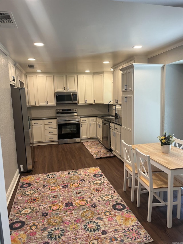 2715 Deer Xing, El Dorado, AR 71730 - kitchen featuring stainless steel appliances, dark wood finished floors, dark countertops, a sink, and recessed lighting