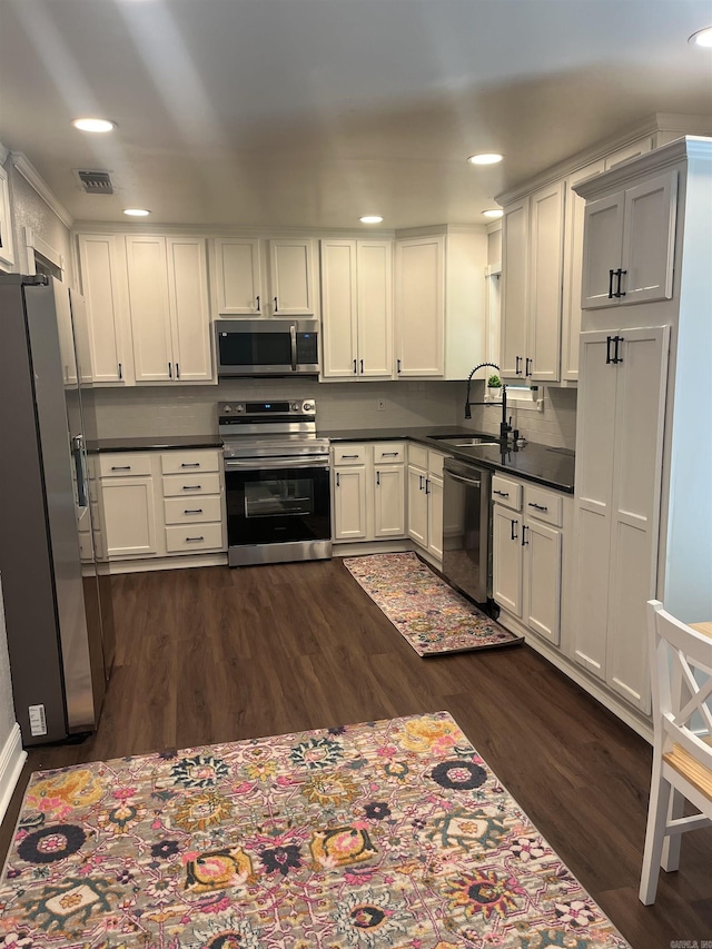 2715 Deer Xing, El Dorado, AR 71730 - kitchen featuring appliances with stainless steel finishes, a sink, dark wood finished floors, dark countertops, and white cabinetry