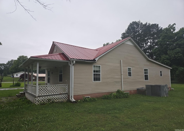 1851 W Clay, Piggott, AR 72454 - view of home's exterior with cooling unit, a lawn, covered porch, and metal roof