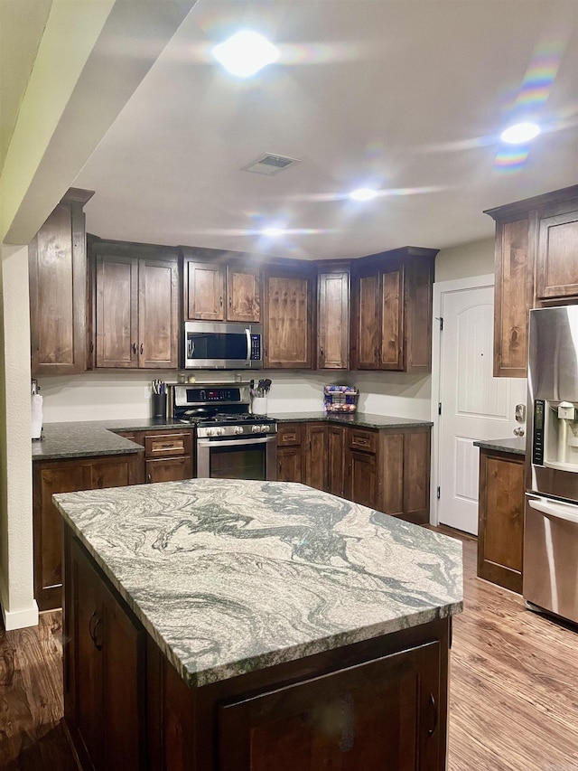 88 Cobblestone Rd, Plumerville, AR 72127 - kitchen with stainless steel appliances, light wood-style floors, dark stone countertops, and a center island