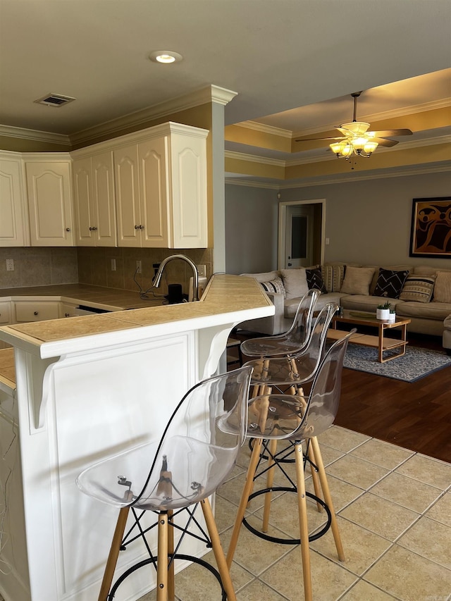11 Willow Cv, Cabot, AR 72023 - kitchen featuring ornamental molding, open floor plan, a peninsula, a breakfast bar, and light tile patterned floors