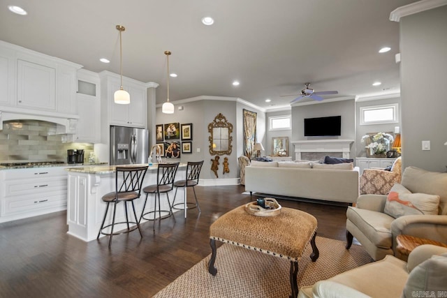 living room with ornamental molding, ceiling fan, dark wood finished floors, recessed lighting, and baseboards