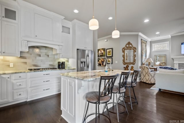 kitchen with stainless steel appliances, crown molding, light stone countertops, open floor plan, and glass insert cabinets