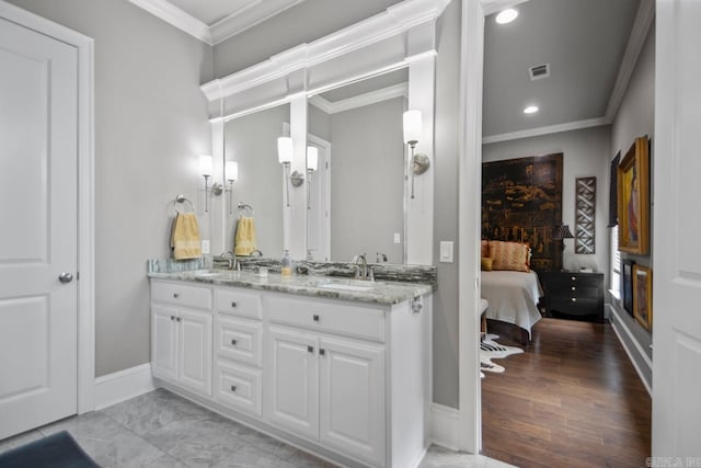 ensuite bathroom featuring double vanity, ornamental molding, baseboards, and recessed lighting