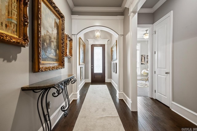 foyer entrance with arched walkways, dark wood-type flooring, ornamental molding, and ceiling fan