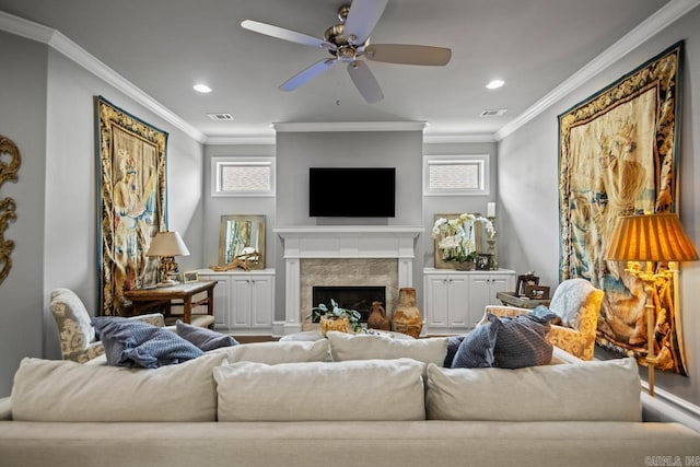 living room with plenty of natural light, crown molding, a premium fireplace, recessed lighting, and a ceiling fan
