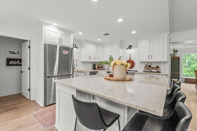 14320 Bradley Rd, Maumelle, AR 72113 - kitchen featuring freestanding refrigerator, white cabinetry, light wood-style floors, decorative backsplash, and recessed lighting
