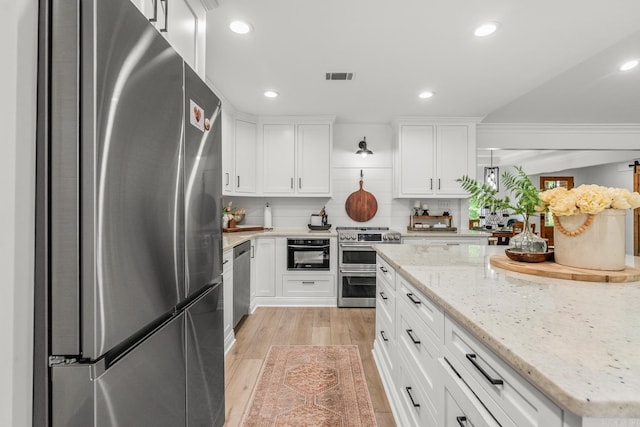 14320 Bradley Rd, Maumelle, AR 72113 - kitchen featuring stainless steel appliances, recessed lighting, light wood finished floors, white cabinetry, and light stone counters
