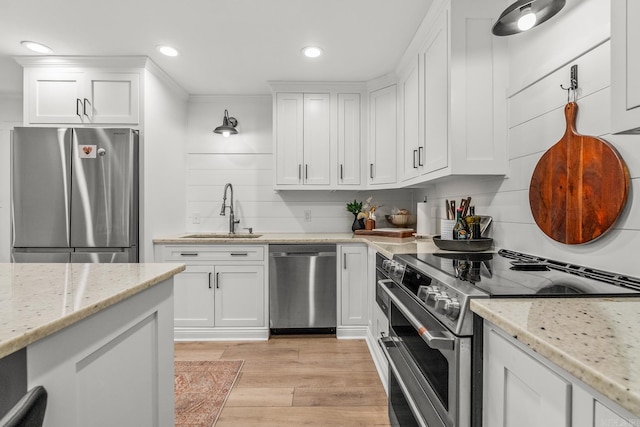 14320 Bradley Rd, Maumelle, AR 72113 - kitchen with appliances with stainless steel finishes, a sink, white cabinets, light wood-style flooring, and recessed lighting