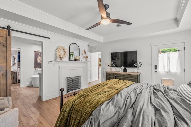 14320 Bradley Rd, Maumelle, AR 72113 - bedroom with a raised ceiling, ornamental molding, a barn door, light wood-type flooring, and a ceiling fan