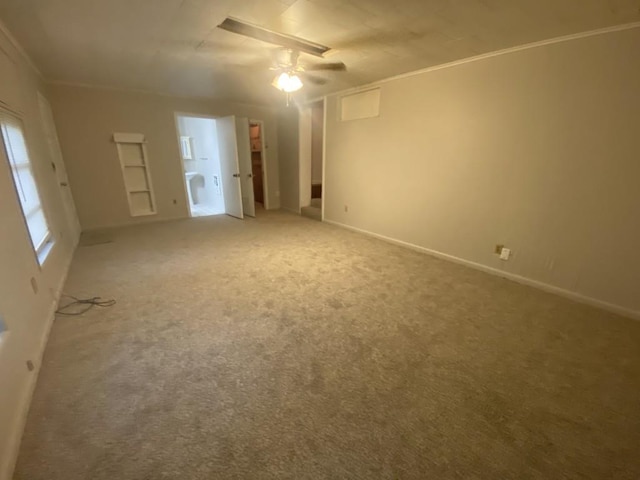 carpeted spare room featuring ceiling fan, crown molding, baseboards, and built in shelves