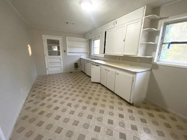 kitchen featuring open shelves, light countertops, white cabinetry, baseboards, and a sink