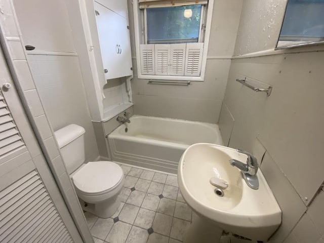 full bath featuring toilet, a bath, tile patterned flooring, and tile walls