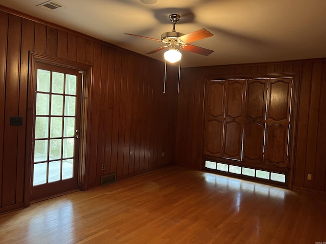 816 W 36th Ave, Pine Bluff, AR 71603 - empty room with light wood-type flooring, plenty of natural light, a ceiling fan, and wood walls
