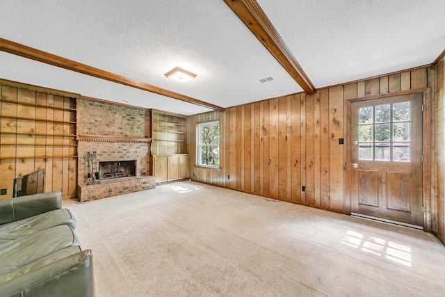 17 Point S Ct, Little Rock, AR 72211 - unfurnished living room with a textured ceiling, wood walls, a fireplace, carpet flooring, and beam ceiling