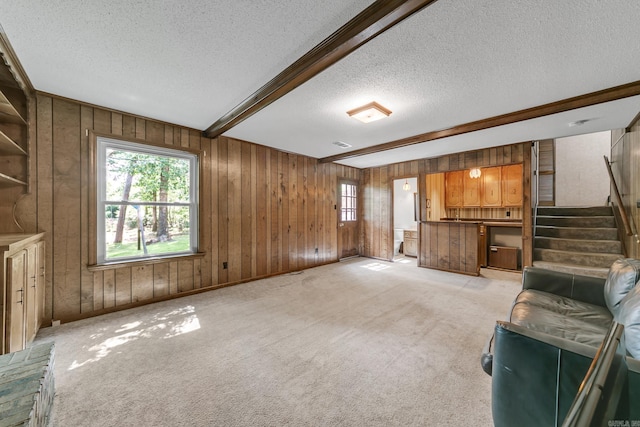 17 Point S Ct, Little Rock, AR 72211 - unfurnished living room featuring a textured ceiling, wooden walls, stairway, beam ceiling, and light carpet