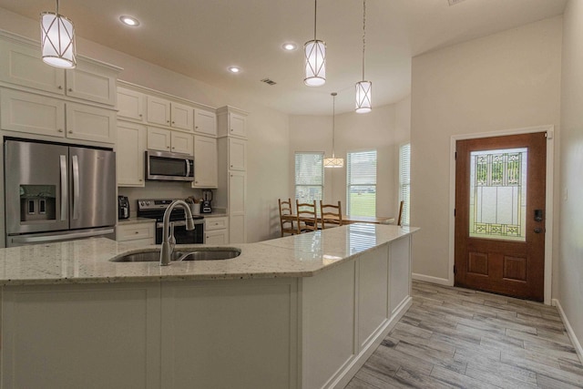 205 Capitol Cv, Jonesboro, AR 72401 - kitchen featuring stainless steel appliances, white cabinetry, light wood-style floors, recessed lighting, and light stone countertops