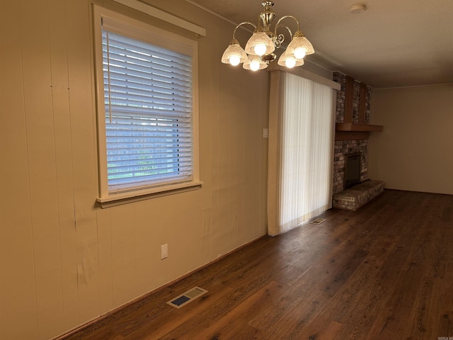 913 Schriner Ct, North Little Rock, AR 72116 - unfurnished living room featuring dark wood-type flooring, a chandelier, and a fireplace with raised hearth