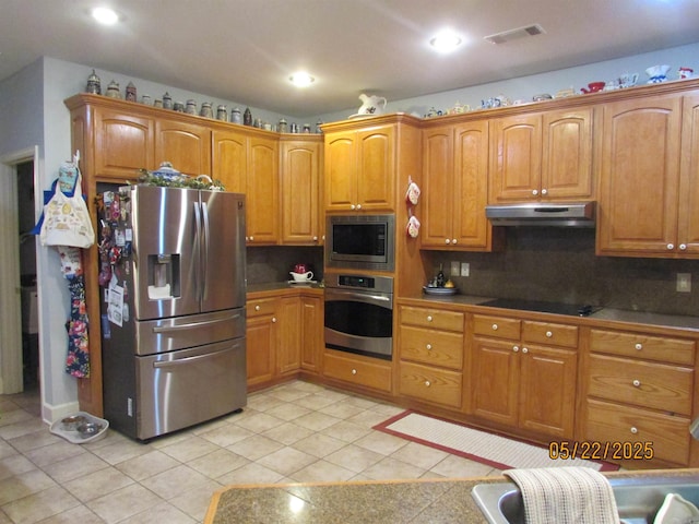 145 Eagles Nest Cv, Austin, AR 72007 - kitchen with appliances with stainless steel finishes, under cabinet range hood, light tile patterned floors, backsplash, and brown cabinets