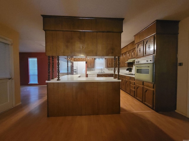 1008 W A Ave, North Little Rock, AR 72116 - kitchen with oven, white fridge with ice dispenser, light wood-style flooring, light countertops, and under cabinet range hood