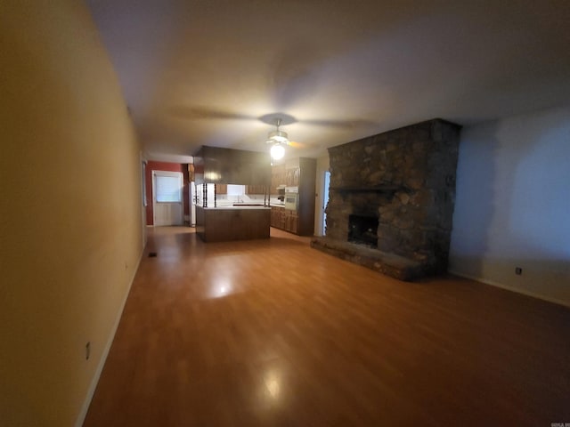 1008 W A Ave, North Little Rock, AR 72116 - unfurnished living room featuring a ceiling fan, wood finished floors, and a stone fireplace