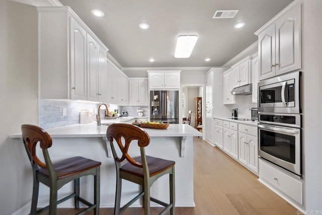 106 Hidden Falls Ln, Maumelle, AR 72113 - kitchen featuring appliances with stainless steel finishes, a peninsula, under cabinet range hood, a kitchen bar, and white cabinets