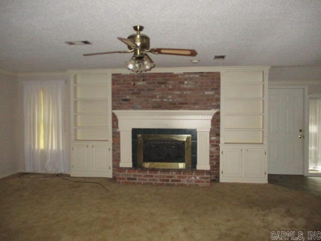 unfurnished living room with carpet flooring, a ceiling fan, a fireplace, a textured ceiling, and crown molding