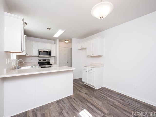 1121 Stewart St, Benton, AR 72015 - kitchen with appliances with stainless steel finishes, dark wood-type flooring, light countertops, a peninsula, and white cabinets
