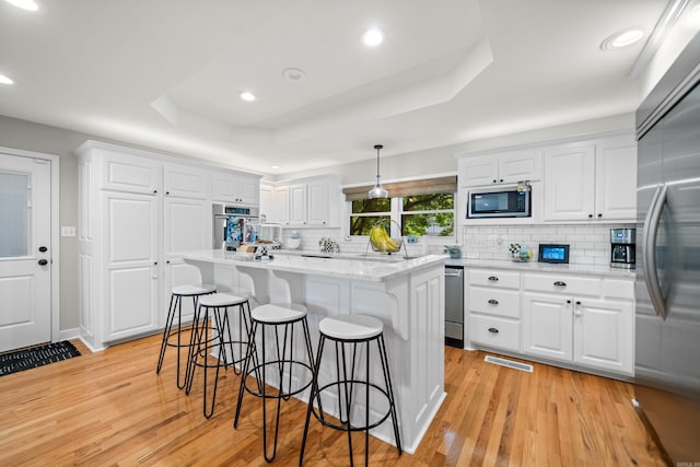 308 Bellaire, Hot Springs, AR 71901 - kitchen featuring stainless steel appliances, light wood-style flooring, a kitchen breakfast bar, white cabinetry, and a tray ceiling