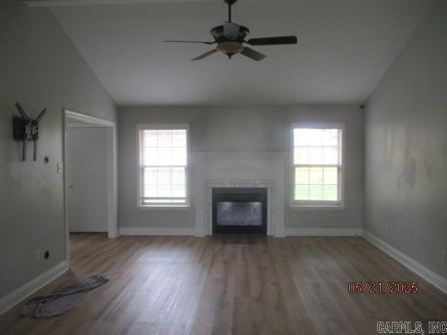 unfurnished living room with wood finished floors, plenty of natural light, a ceiling fan, and vaulted ceiling