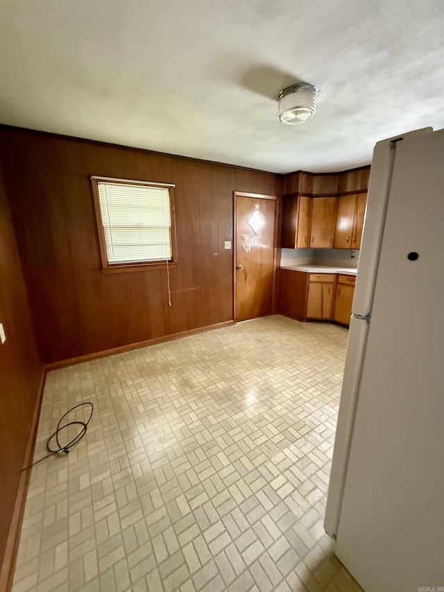 811 Hester St, Jonesboro, AR 72401 - kitchen featuring freestanding refrigerator, brick patterned floors, light countertops, brown cabinets, and wood walls