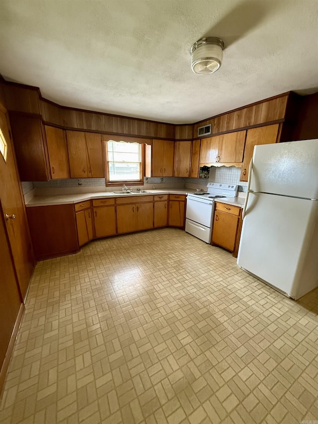 811 Hester St, Jonesboro, AR 72401 - kitchen with white appliances, brick patterned floors, brown cabinets, wood walls, and light countertops