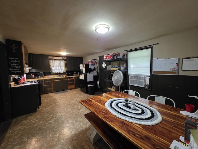 109 S Adams St, Mena, AR 71953 - kitchen featuring light countertops, dark cabinetry, cooling unit, under cabinet range hood, and freestanding refrigerator