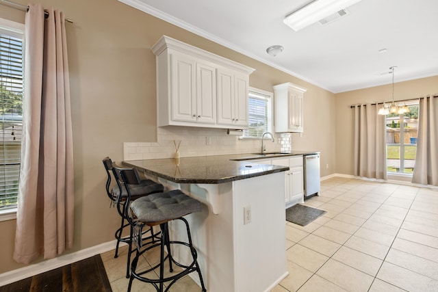 1228 Ridgecrest Dr, Benton, AR 72015 - kitchen with light tile patterned floors, white cabinetry, backsplash, dishwasher, and crown molding