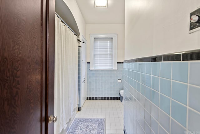 301 W Magnolia St, Rison, AR 71665 - full bath featuring tile patterned floors, tile walls, a shower with curtain, and wainscoting