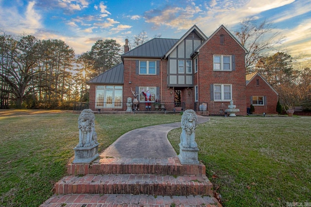301 W Magnolia St, Rison, AR 71665 - tudor-style house featuring a standing seam roof, brick siding, a front lawn, and a metal roof