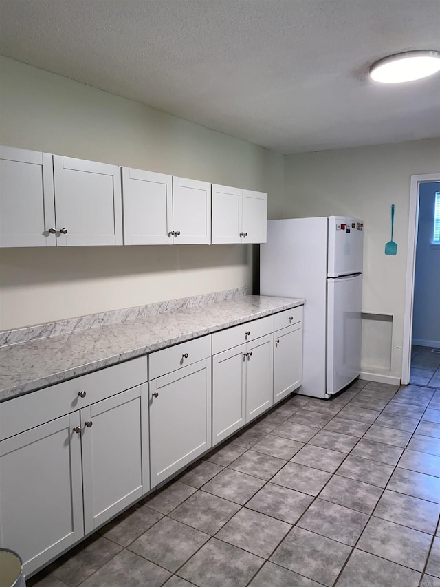 4 Trout, Heber Springs, AR 72543 - kitchen featuring freestanding refrigerator, white cabinetry, light tile patterned floors, and a textured ceiling