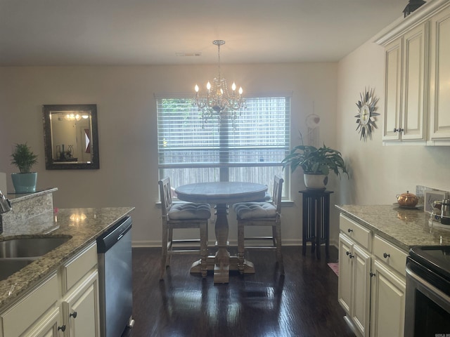 kitchen with appliances with stainless steel finishes, a chandelier, dark wood finished floors, and stone countertops