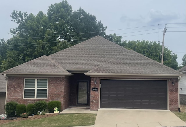 ranch-style house with roof with shingles, brick siding, an attached garage, and driveway