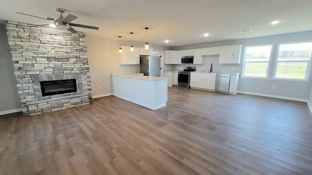 705 Liberty, Marked Tree, AR 72365 - kitchen with stainless steel appliances, ceiling fan, a peninsula, a fireplace, and white cabinets