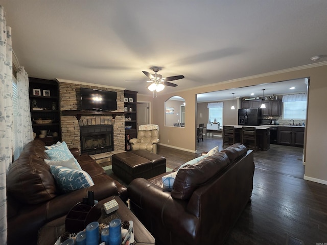 274 Hopewell Hollow Rd, Norfork, AR 72658 - living room featuring dark wood-type flooring, ceiling fan, a stone fireplace, ornamental molding, and arched walkways