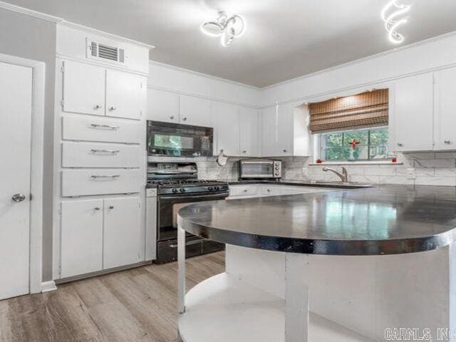 22 Nob Hill Cv, Little Rock, AR 72205 - kitchen featuring black microwave, gas stove, dark countertops, a peninsula, and light wood-type flooring