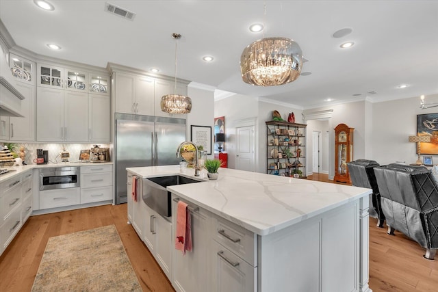 4260 Weldon Cv, Jonesboro, AR 72404 - kitchen featuring appliances with stainless steel finishes, ornamental molding, a chandelier, a center island with sink, and light wood-style flooring