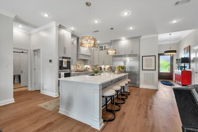 4260 Weldon Cv, Jonesboro, AR 72404 - kitchen featuring stainless steel appliances, a chandelier, ornamental molding, light wood-type flooring, and a kitchen bar