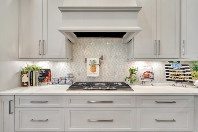 4260 Weldon Cv, Jonesboro, AR 72404 - kitchen with custom range hood, stainless steel gas stovetop, decorative backsplash, and white cabinetry