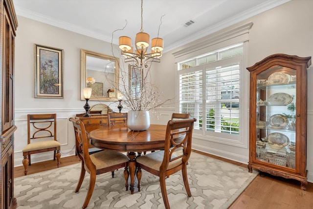 4260 Weldon Cv, Jonesboro, AR 72404 - dining room featuring a chandelier, light wood-style floors, crown molding, and a wainscoted wall