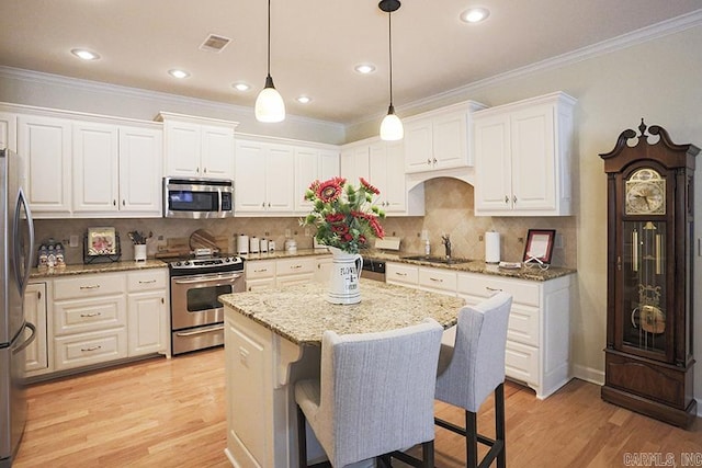 29 Taylor Park Loop, Little Rock, AR 72211 - kitchen featuring stainless steel appliances, a kitchen island, white cabinetry, light wood-style floors, and ornamental molding